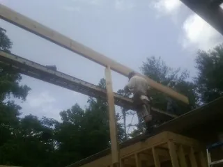 Carpenter setting a ridge beam over a new addition frame — Ice Dam Removal by Roofing Brothers in Saint Benedict