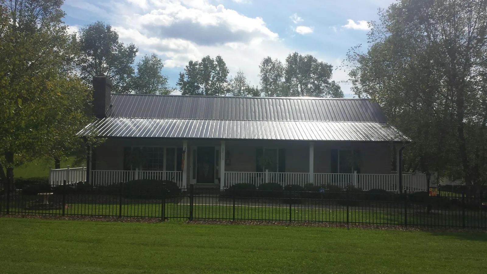 Gray metal roof on a brick ranch with a full width front porch — Gutter Guard Installation work by our crew in Saint Benedict