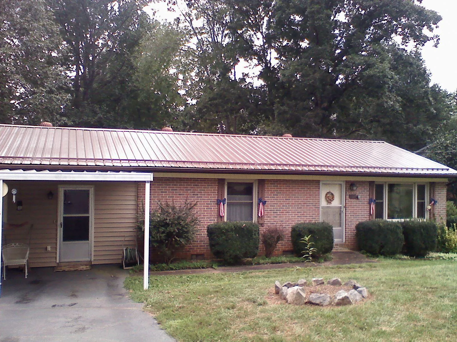 Bronze metal roof and carport on a brick ranch home — Roof Repair work by our crew in Saint Benedict