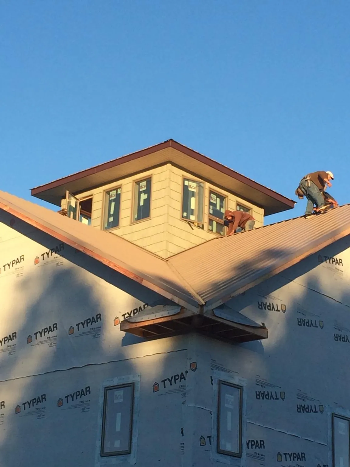 Roofers working around a rooftop cupola on a new metal roof at sunset — Roof Waterproofing in Saint Benedict by Roofing Brothers